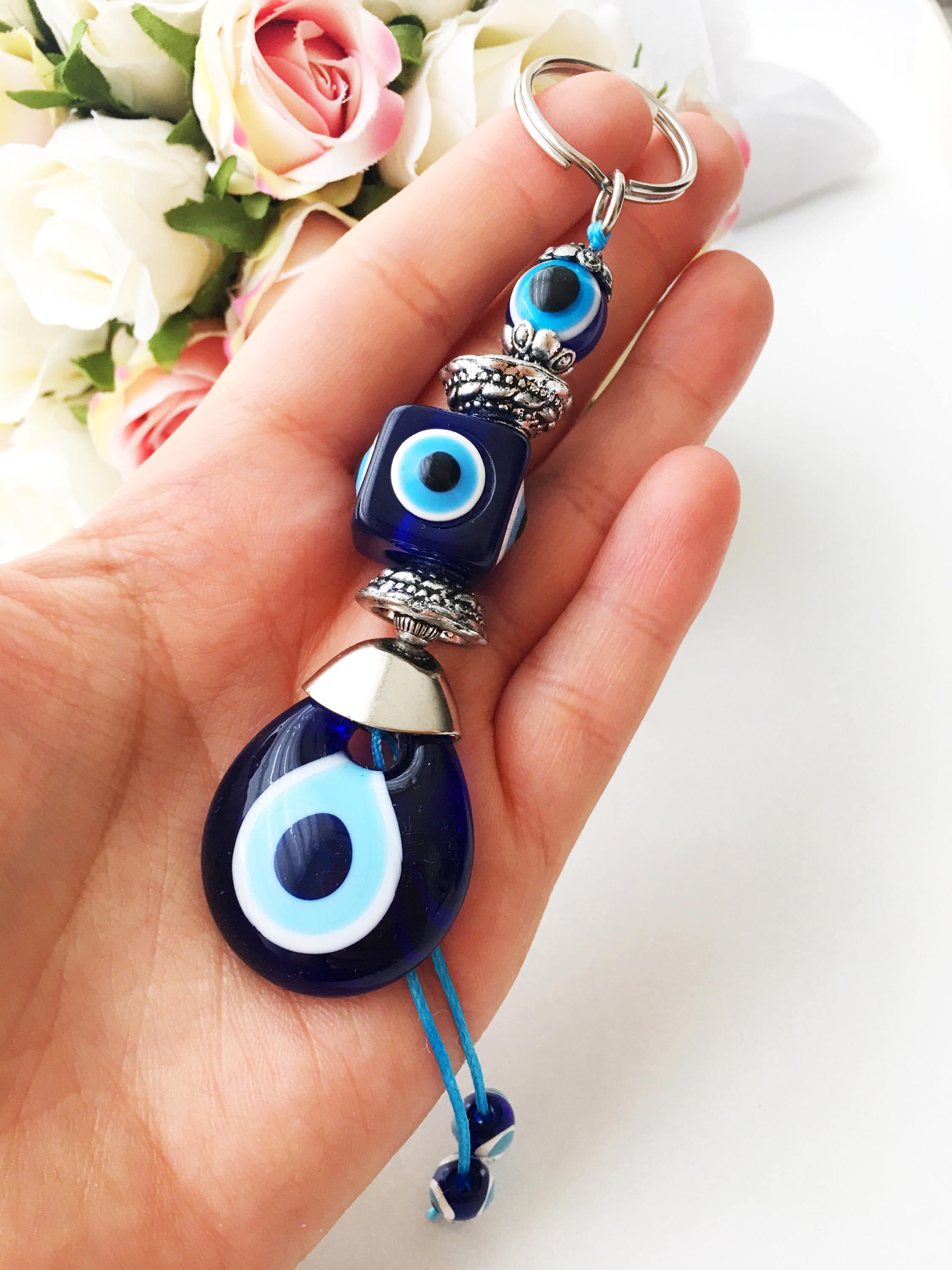 A beautifully crafted Evil Eye keychain featuring vibrant blue and white beads, symbolizing protection and good luck, attached to a silver keyring.