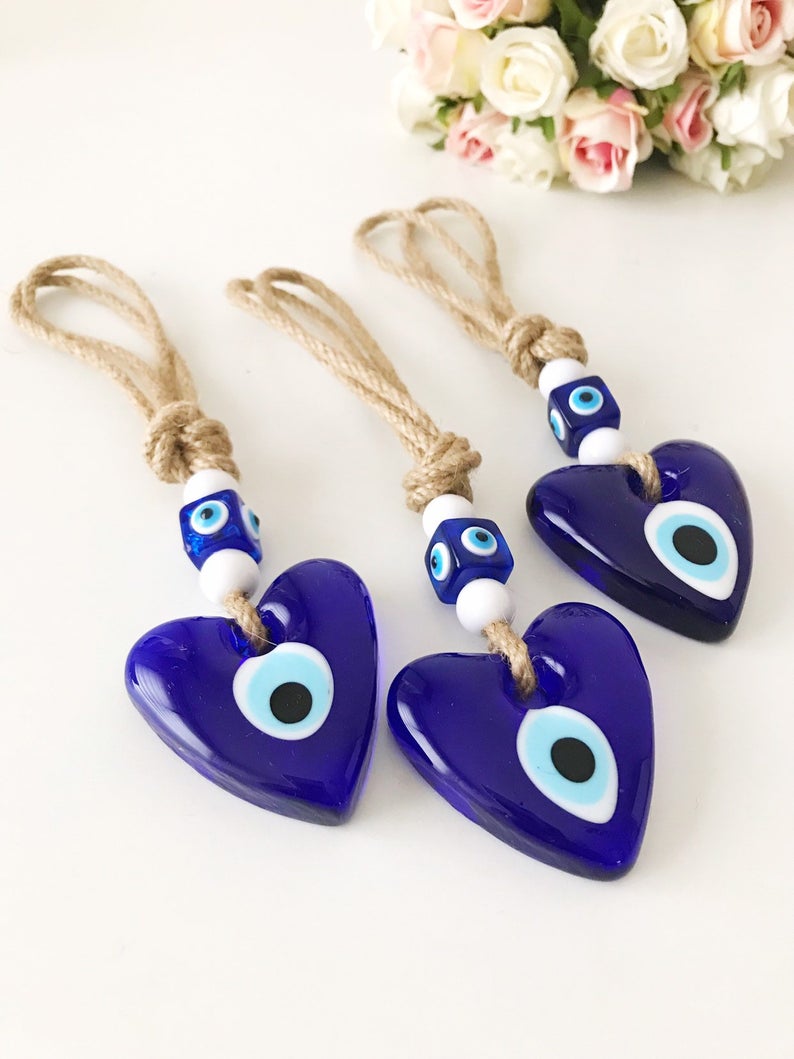 Evil Eye Love wall hanging featuring a heart design with blue evil eye beads and macrame elements, perfect for home decor.