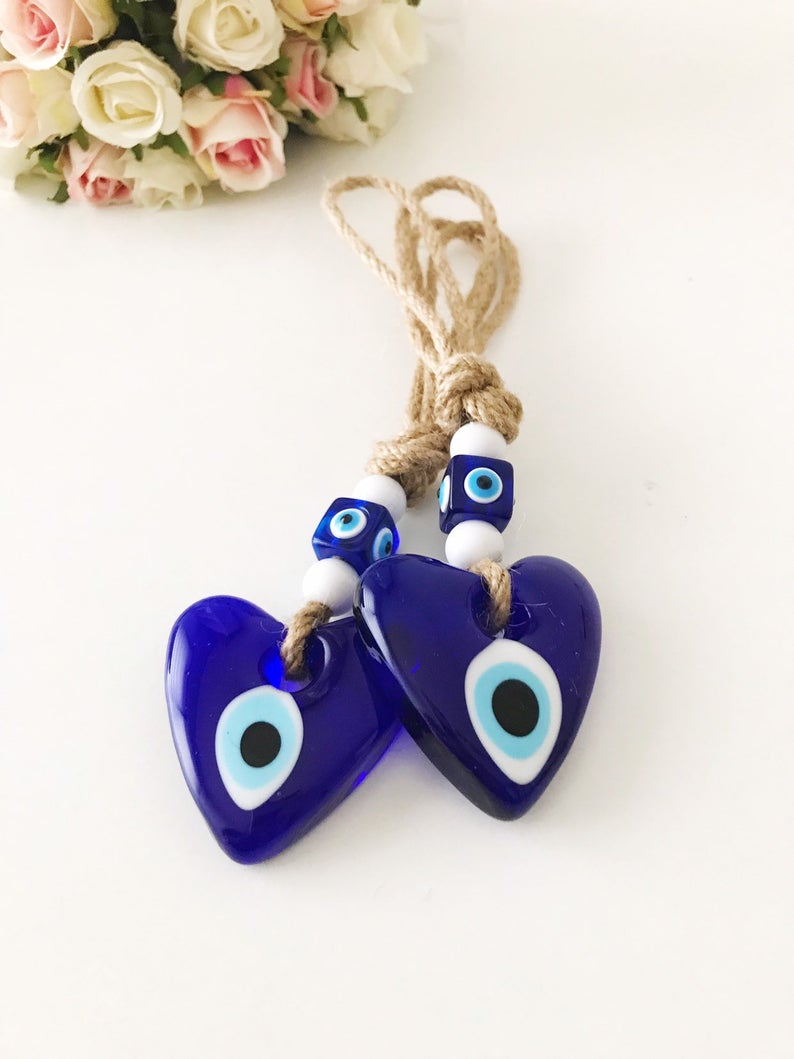 Evil Eye Love wall hanging featuring a heart design with blue evil eye beads and macrame elements, perfect for home decor.