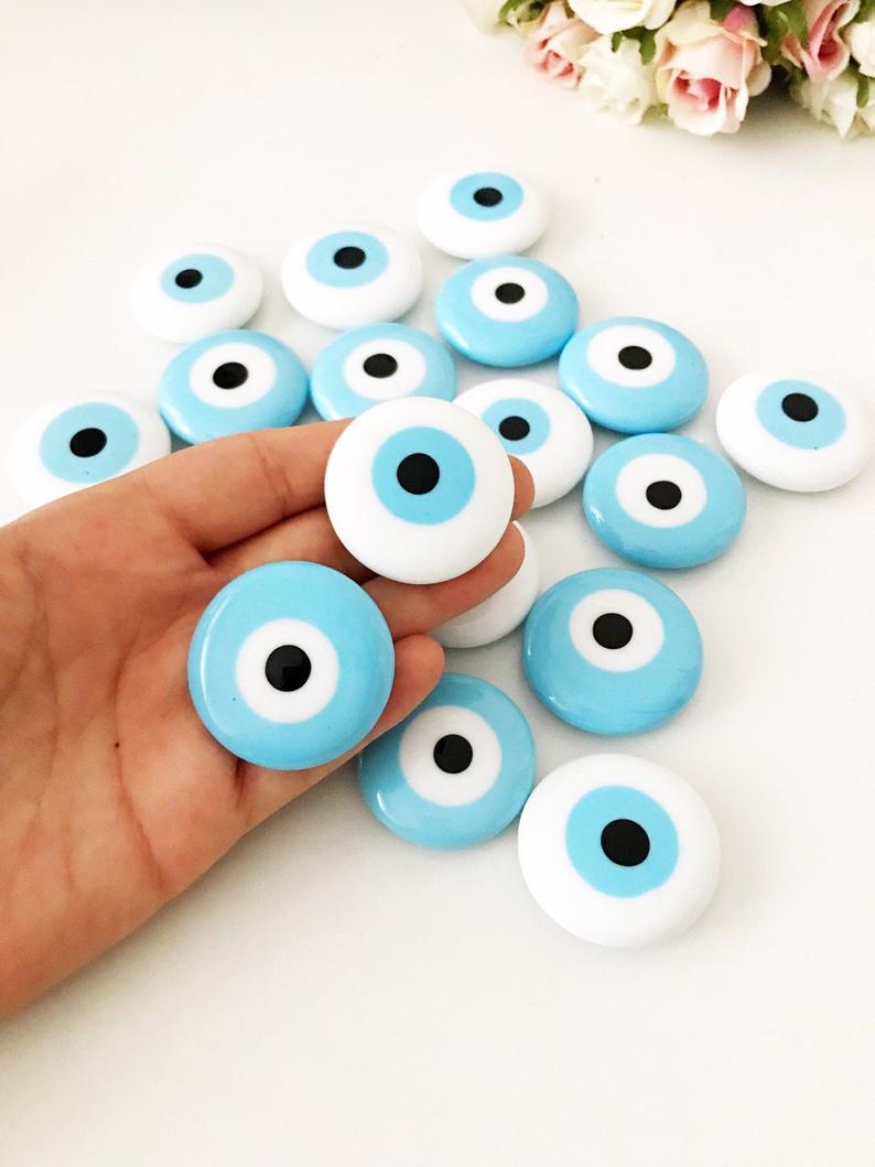 A collection of evil eye magnets in various colors, each featuring the traditional blue and white design, perfect for wedding favors.