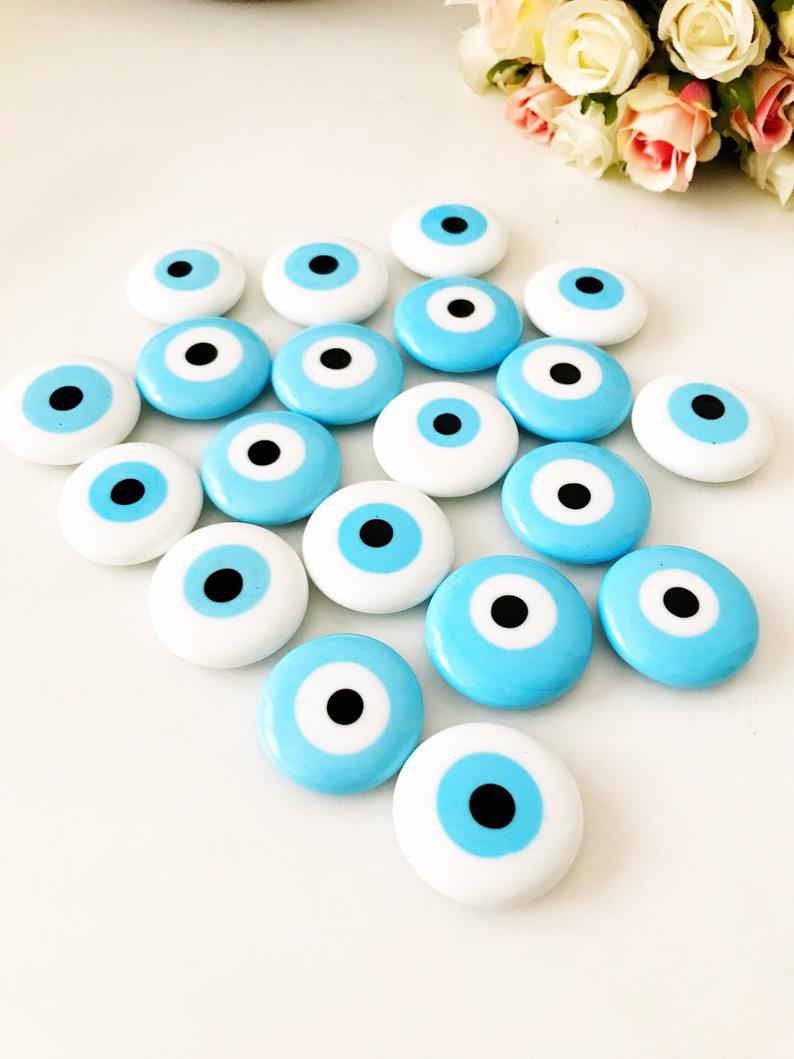 A collection of evil eye magnets in various colors, each featuring the traditional blue and white design, perfect for wedding favors.