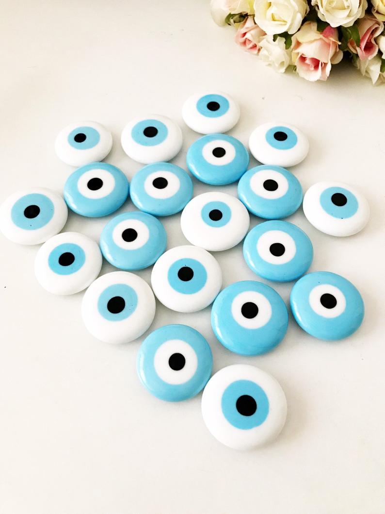 A collection of evil eye magnets in various colors, each featuring the traditional blue and white design, perfect for wedding favors.