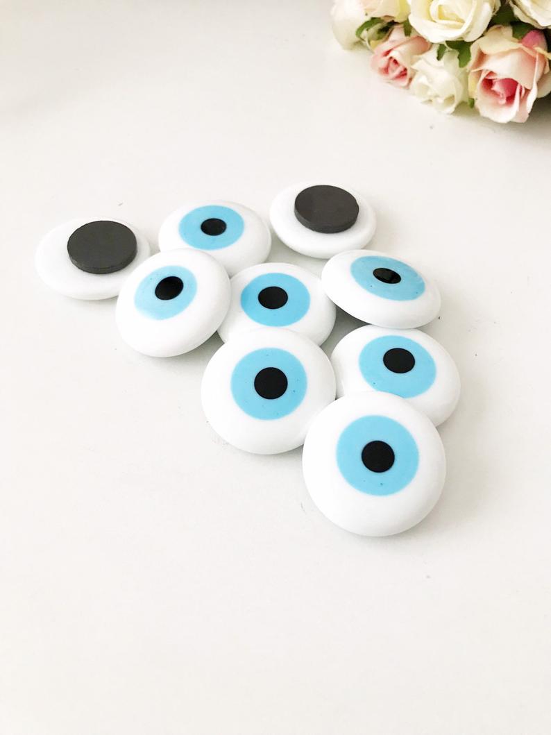 A collection of evil eye magnets in various colors, each featuring the traditional blue and white design, perfect for wedding favors.