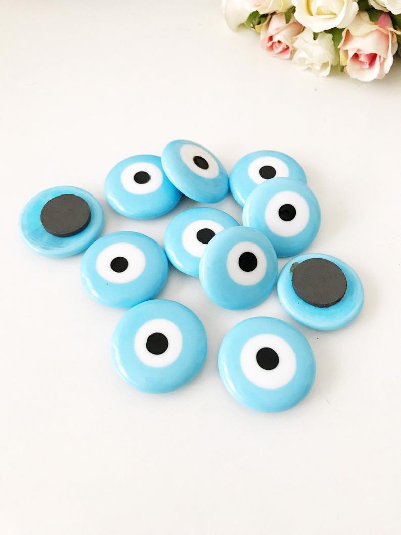 A collection of evil eye magnets in various colors, each featuring the traditional blue and white design, perfect for wedding favors.