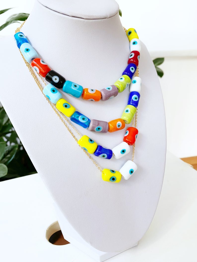 A beautifully handcrafted Evil Eye Necklace featuring colorful Murano tube beads and a stainless steel chain in gold or silver.