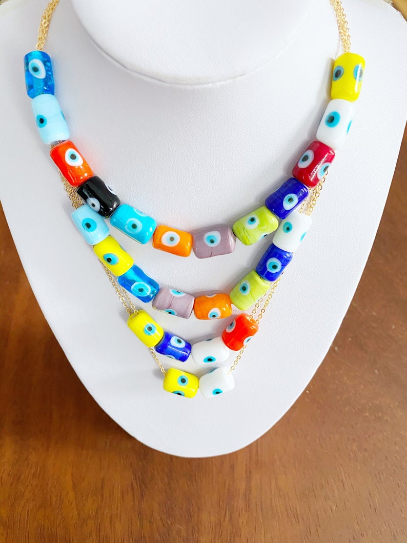 A beautifully handcrafted Evil Eye Necklace featuring colorful Murano tube beads and a stainless steel chain in gold or silver.