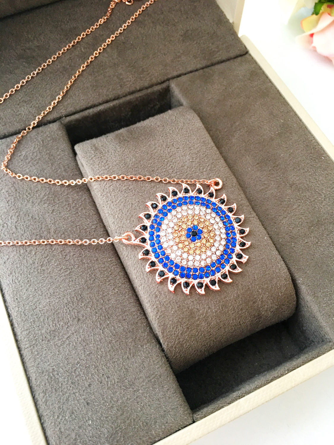 Handmade gold evil eye necklace with zirconia sun pendant, featuring an adjustable chain and unique design.