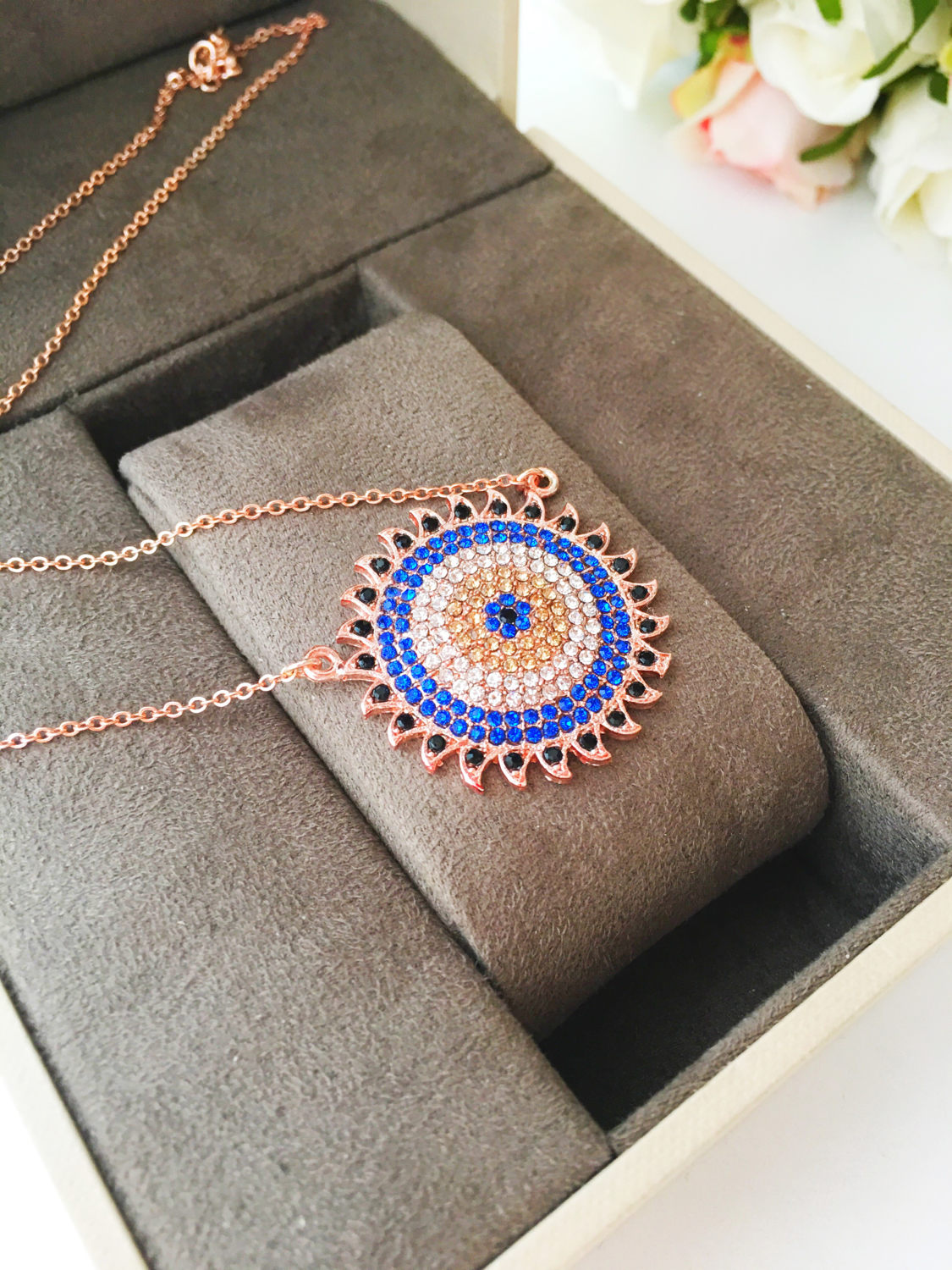 Handmade gold evil eye necklace with zirconia sun pendant, featuring an adjustable chain and unique design.