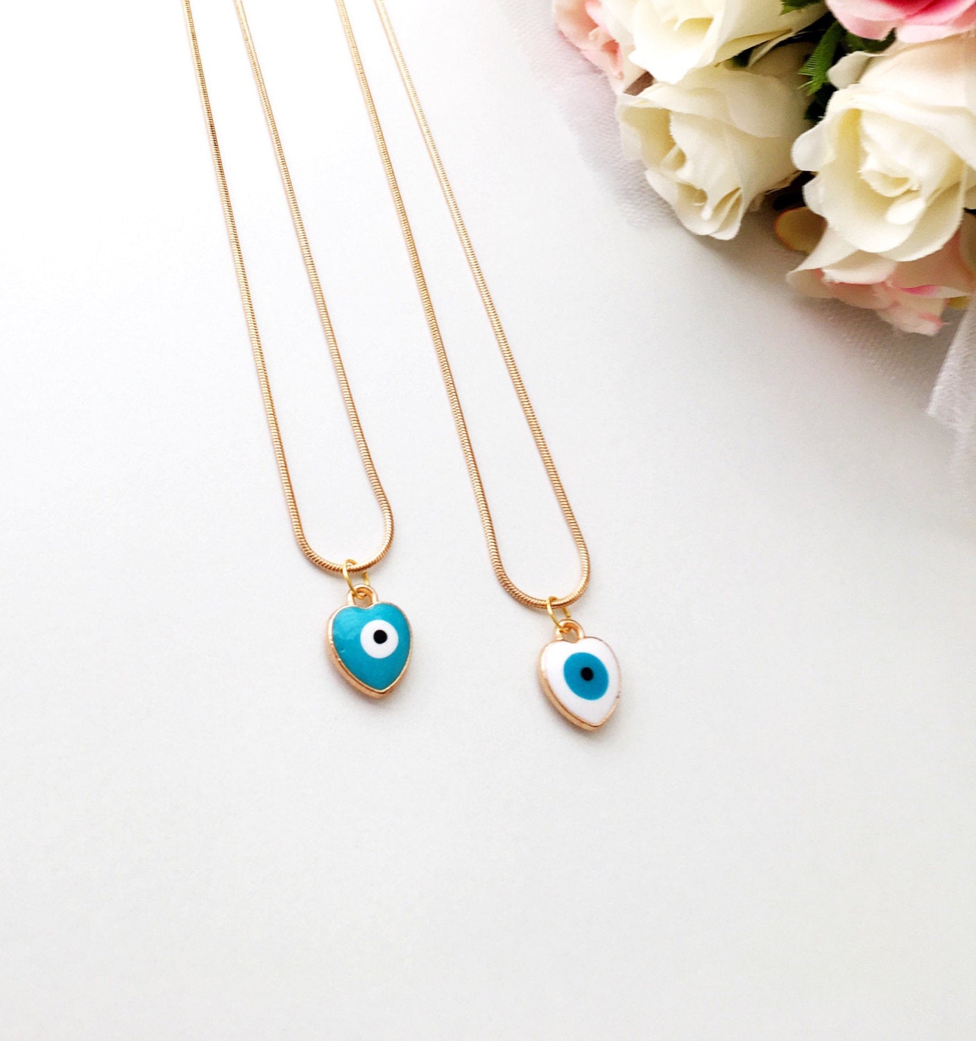 Handmade evil eye necklace featuring a heart charm with white and turquoise enamel on a 22K gold plated chain.