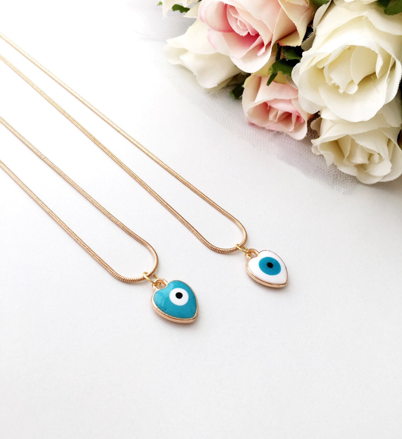 Handmade evil eye necklace featuring a heart charm with white and turquoise enamel on a 22K gold plated chain.