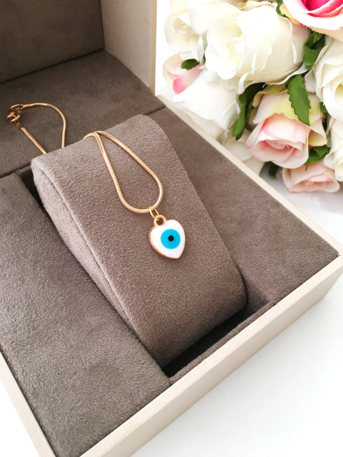 Handmade evil eye necklace featuring a heart charm with white and turquoise enamel on a 22K gold plated chain.