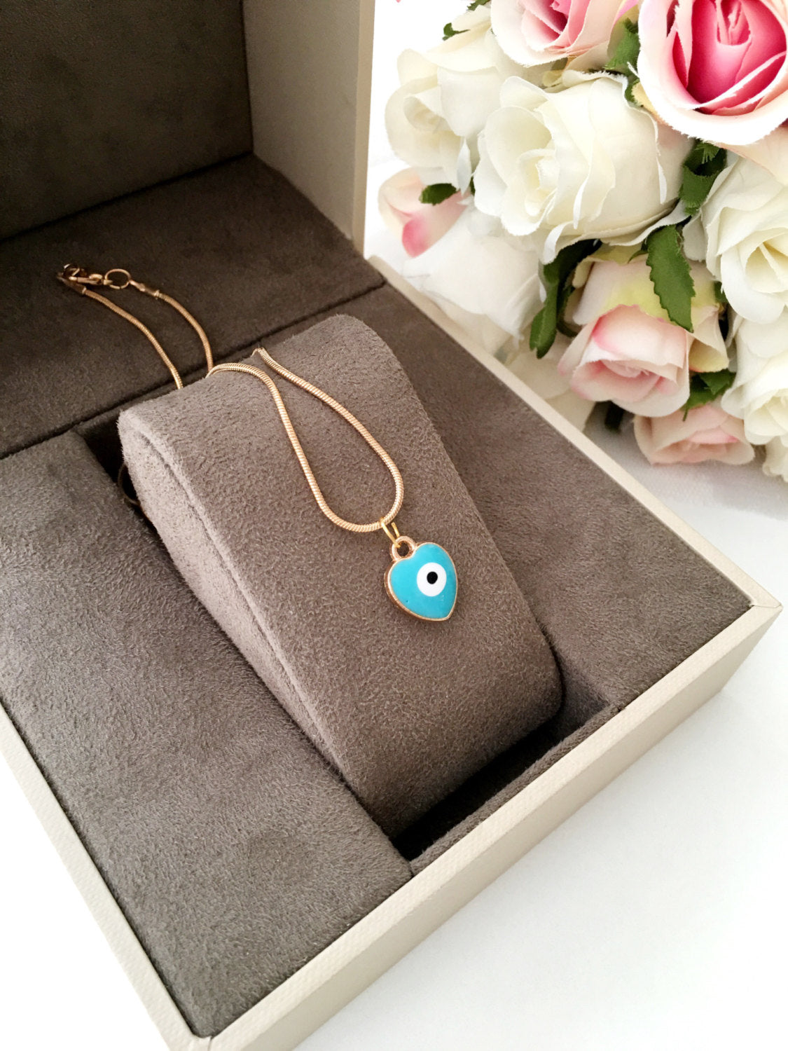 Handmade evil eye necklace featuring a heart charm with white and turquoise enamel on a 22K gold plated chain.