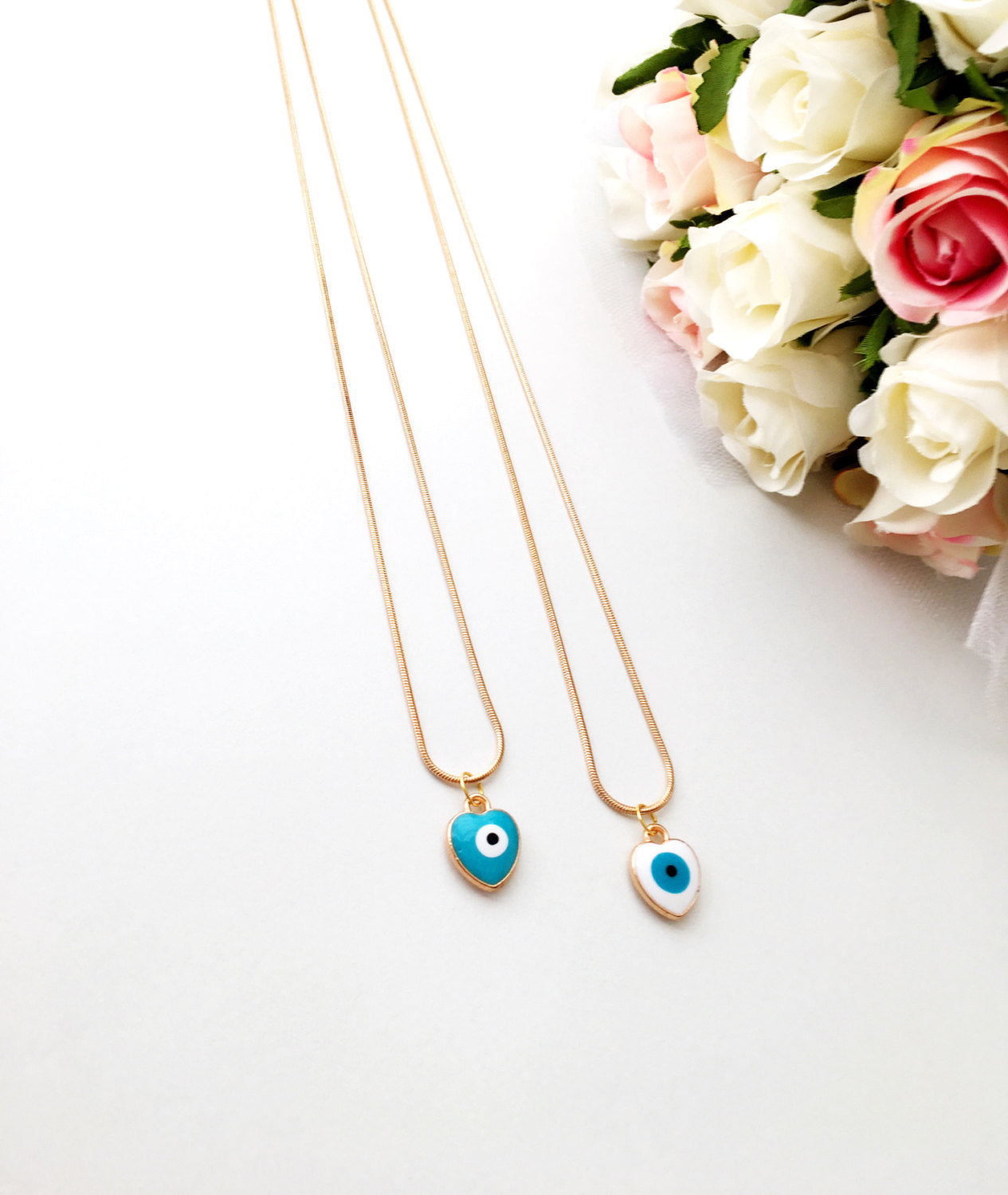 Handmade evil eye necklace featuring a heart charm with white and turquoise enamel on a 22K gold plated chain.