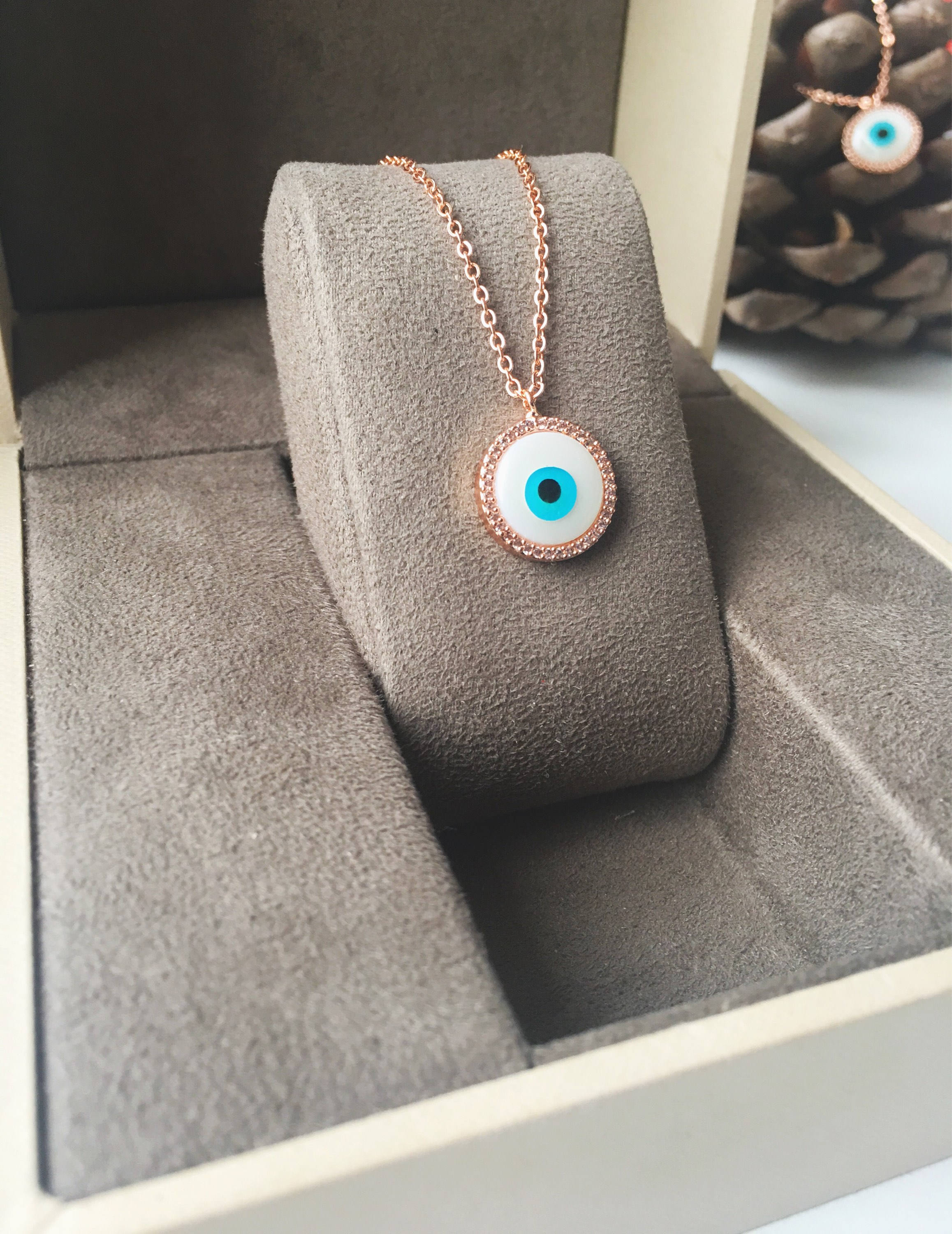 Elegant evil eye necklace featuring a mother of pearl charm and rose gold clover design, showcasing its unique handmade craftsmanship.