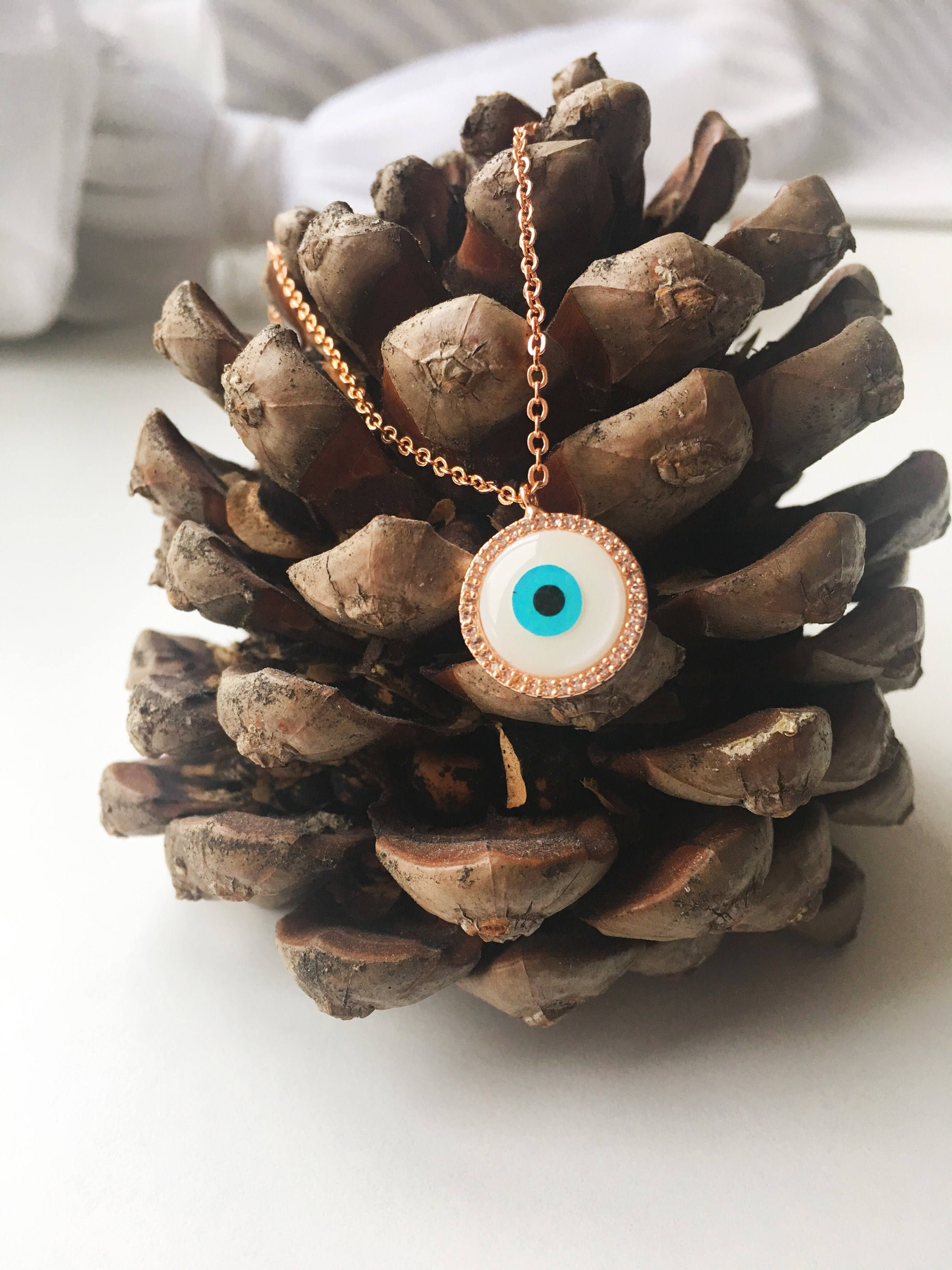 Elegant evil eye necklace featuring a mother of pearl charm and rose gold clover design, showcasing its unique handmade craftsmanship.