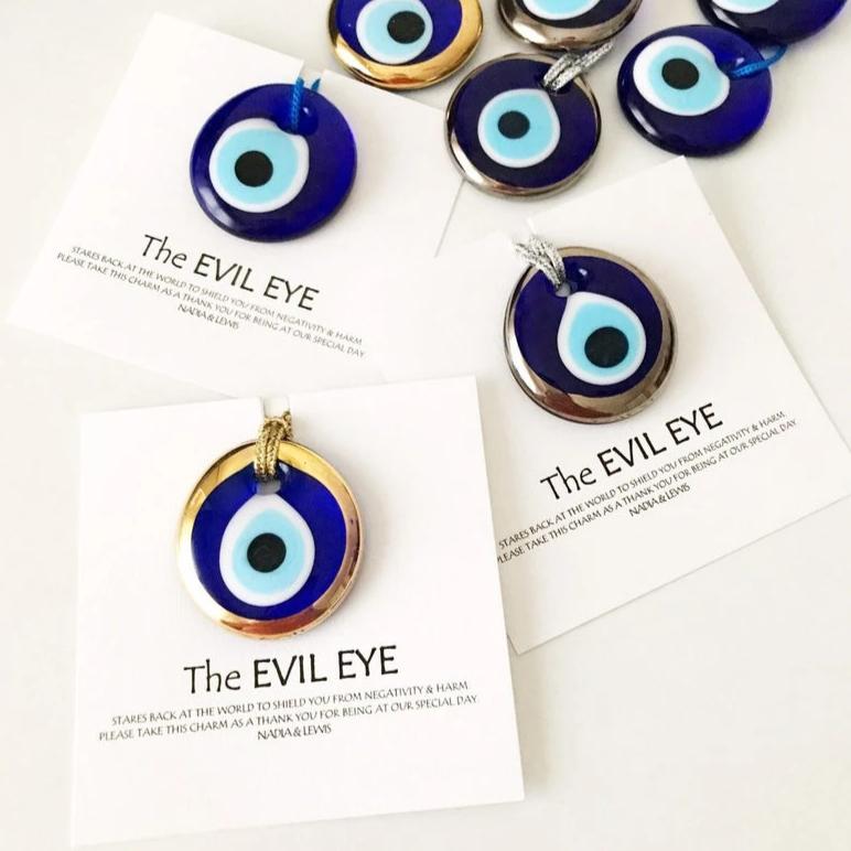 A collection of Evil Eye personalized wedding favors featuring blue glass beads with gold trim, beautifully arranged for display.