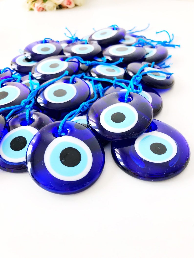 A collection of Evil Eye personalized wedding favors featuring blue glass beads with gold trim, beautifully arranged for display.