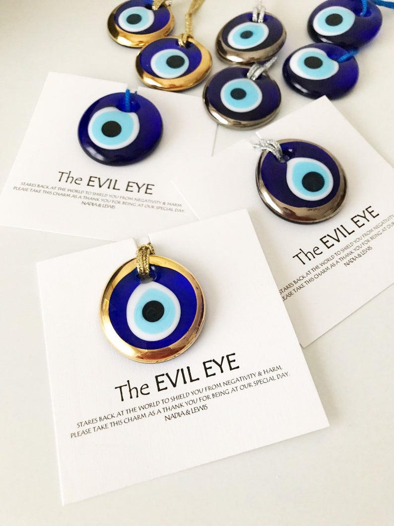 A collection of Evil Eye personalized wedding favors featuring blue glass beads with gold trim, beautifully arranged for display.