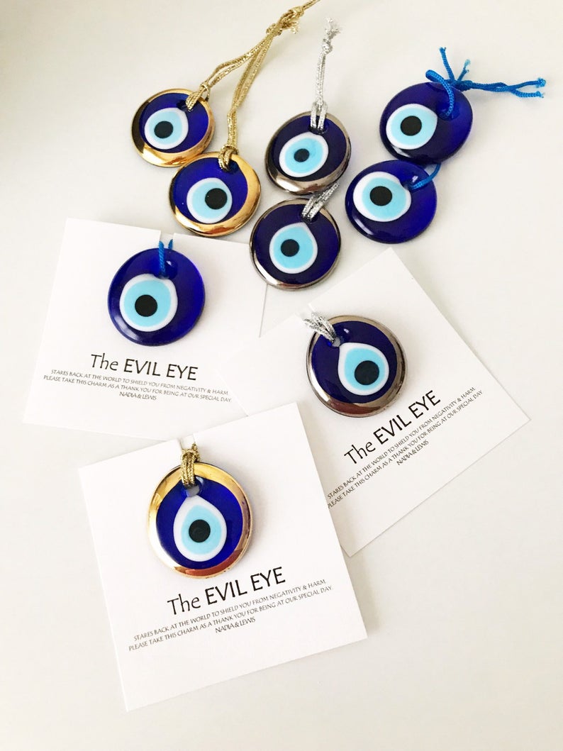 A collection of Evil Eye personalized wedding favors featuring blue glass beads with gold trim, beautifully arranged for display.