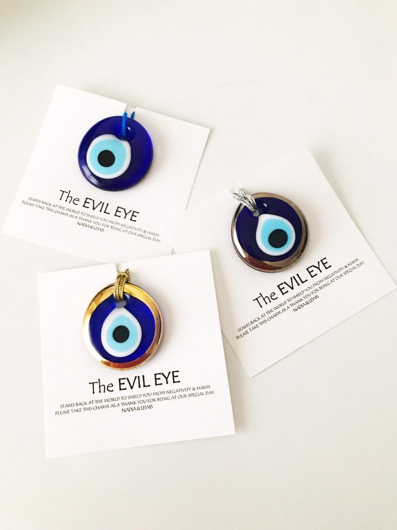 A collection of Evil Eye personalized wedding favors featuring blue glass beads with gold trim, beautifully arranged for display.