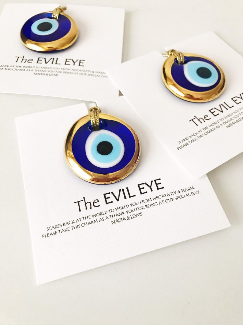 A collection of Evil Eye personalized wedding favors featuring blue glass beads with gold trim, beautifully arranged for display.