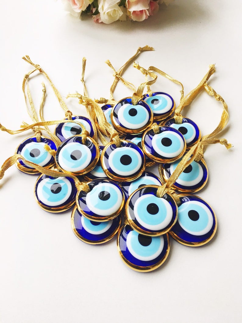 A collection of Evil Eye personalized wedding favors featuring blue glass beads with gold trim, beautifully arranged for display.