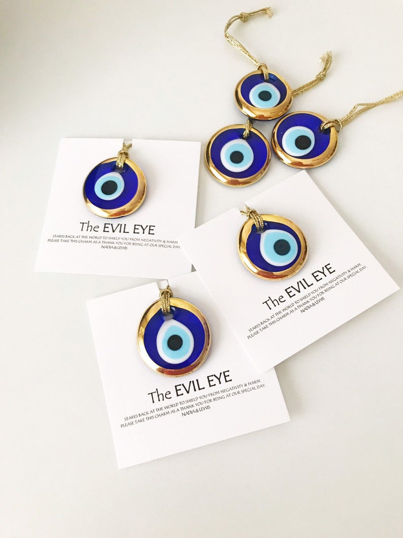 A collection of Evil Eye personalized wedding favors featuring blue glass beads with gold trim, beautifully arranged for display.