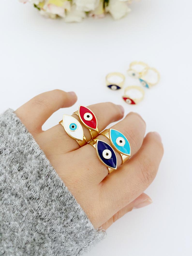 Adjustable Evil Eye Ring with gold band and colorful evil eye bead, available in blue, white, turquoise, and red.