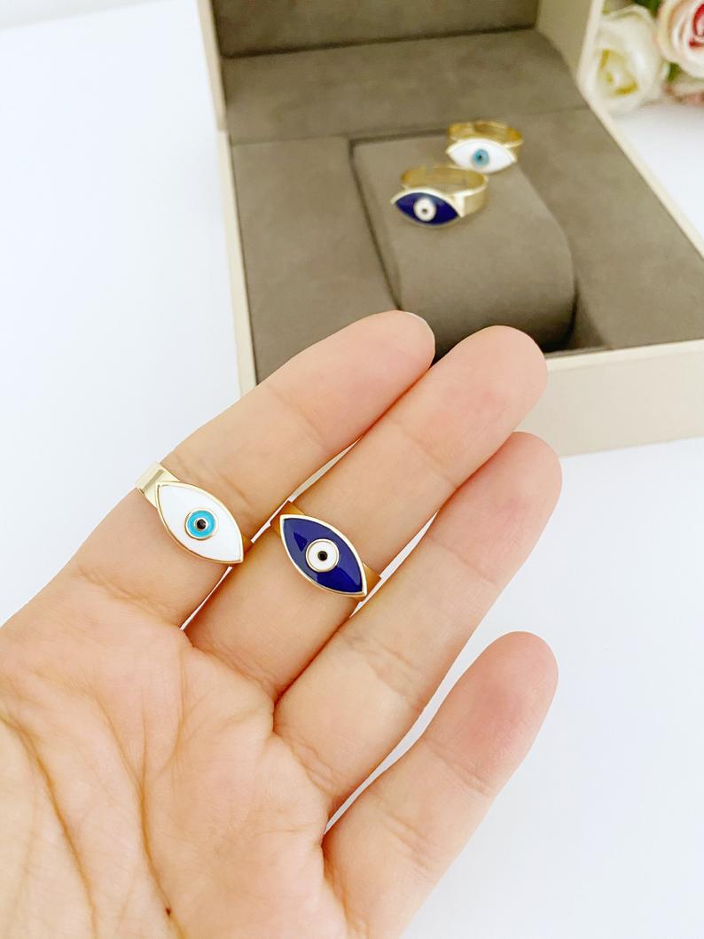 Adjustable Evil Eye Ring with gold band and colorful evil eye bead, available in blue, white, turquoise, and red.