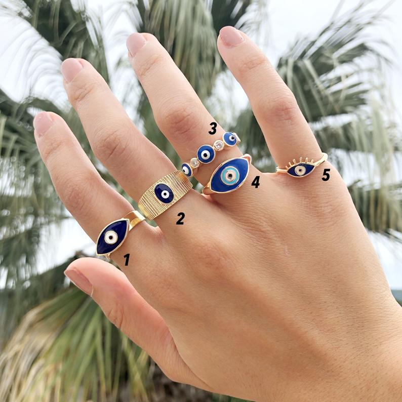 A beautiful set of gold adjustable evil eye rings featuring blue evil eye symbols, showcasing five unique styles for everyday wear.