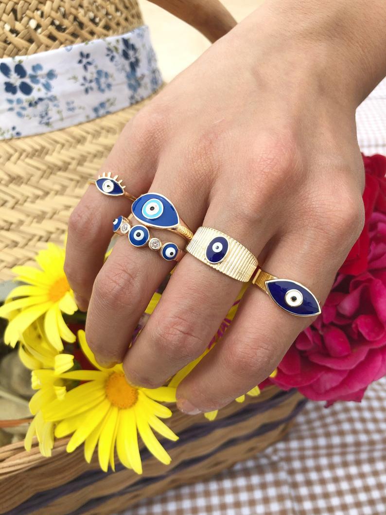 A beautiful set of gold adjustable evil eye rings featuring blue evil eye symbols, showcasing five unique styles for everyday wear.