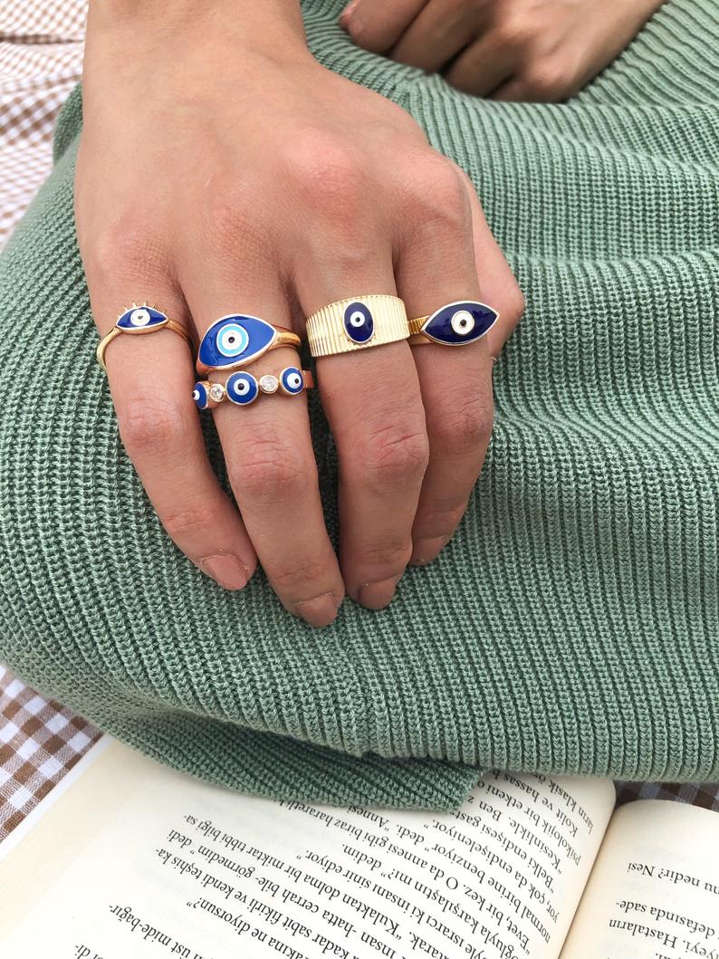 A beautiful set of gold adjustable evil eye rings featuring blue evil eye symbols, showcasing five unique styles for everyday wear.