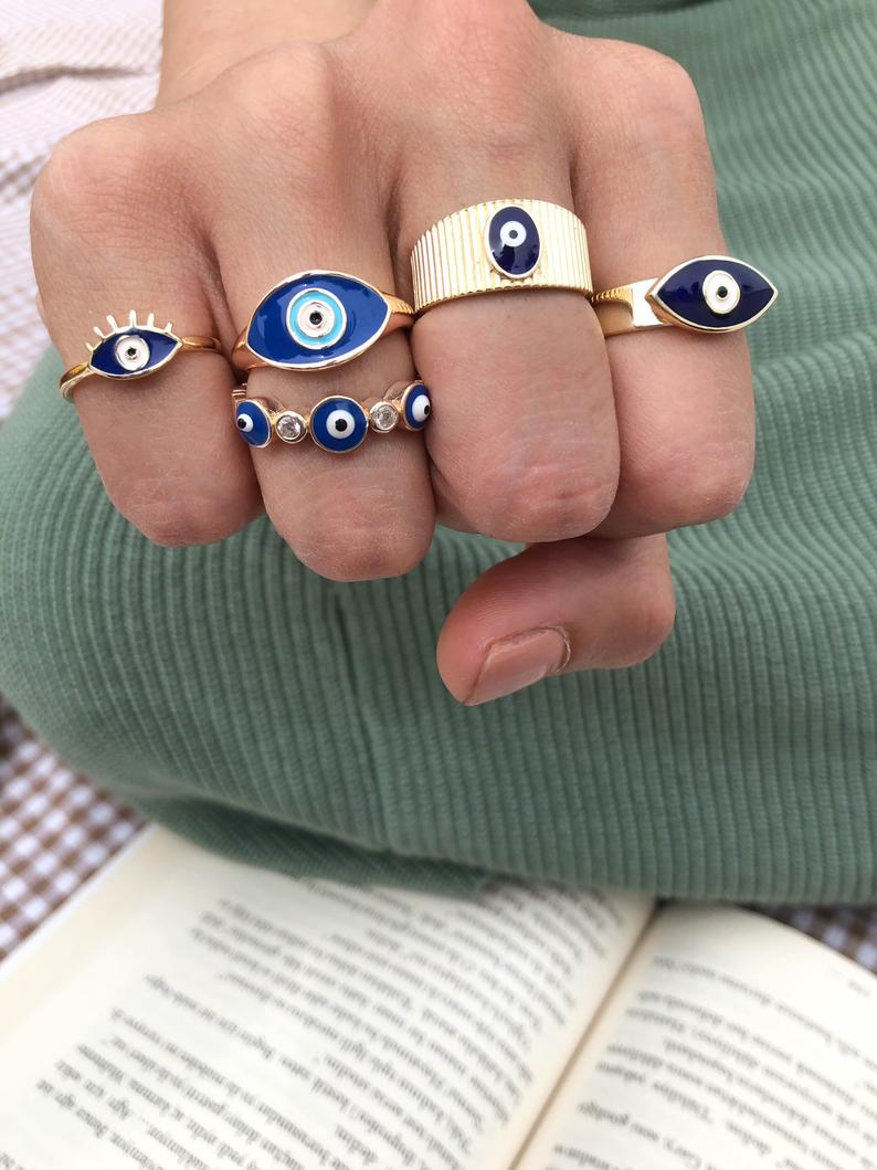 A beautiful set of gold adjustable evil eye rings featuring blue evil eye symbols, showcasing five unique styles for everyday wear.