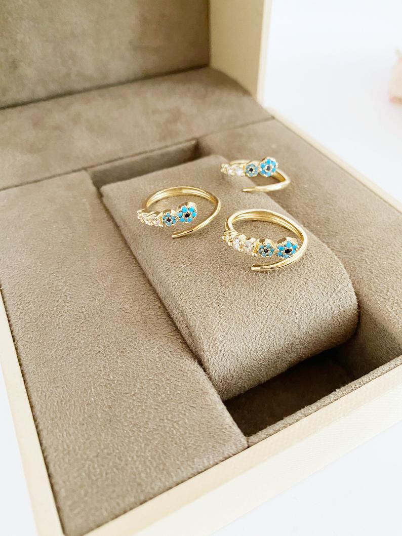 A beautiful adjustable evil eye ring featuring a zircon charm and turquoise bead, set in a gold finish, perfect for stylish protection.