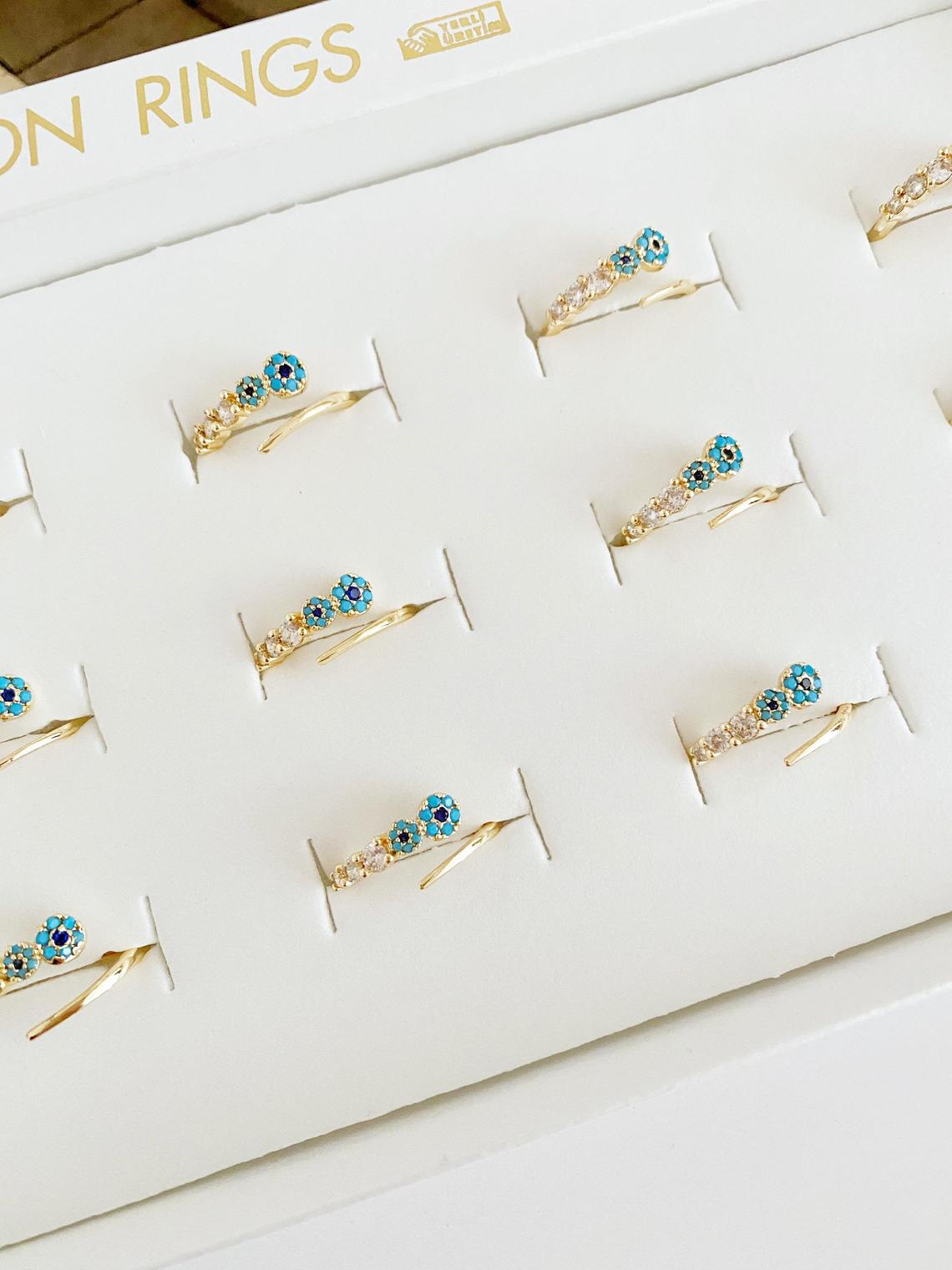 A beautiful adjustable evil eye ring featuring a zircon charm and turquoise bead, set in a gold finish, perfect for stylish protection.