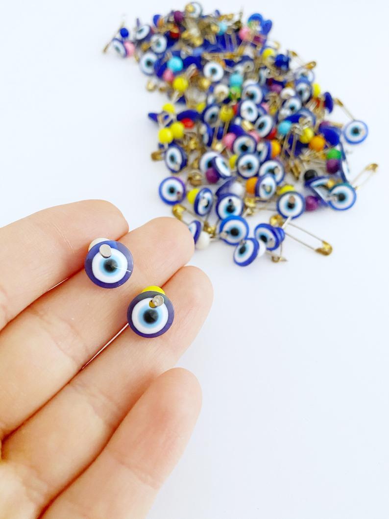 A collection of 100 blue evil eye safety pins, featuring resin beads and gold plating, perfect for weddings and baby showers.