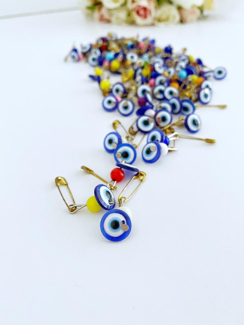 A collection of 100 blue evil eye safety pins, featuring resin beads and gold plating, perfect for weddings and baby showers.