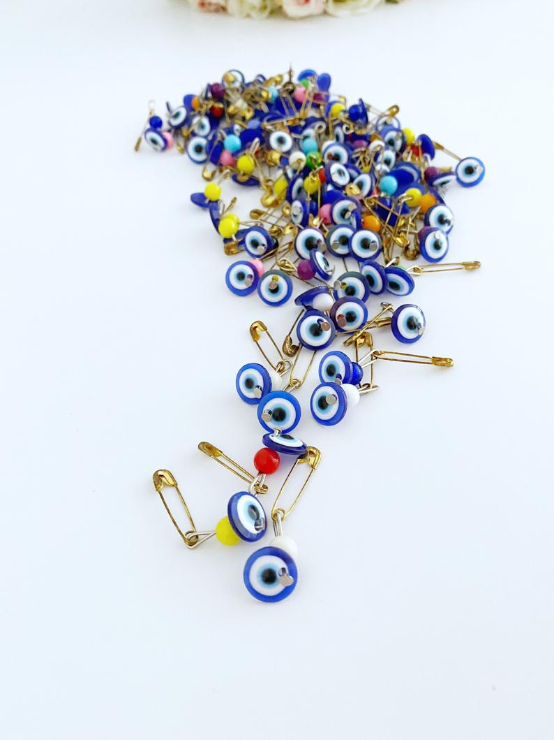 A collection of 100 blue evil eye safety pins, featuring resin beads and gold plating, perfect for weddings and baby showers.