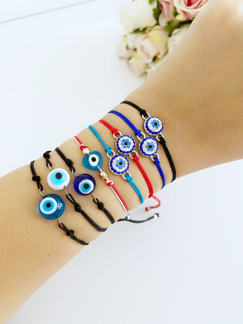 Evil Eye Thread Bracelet featuring a blue evil eye bead and adjustable string, adorned with a Hamsa charm.