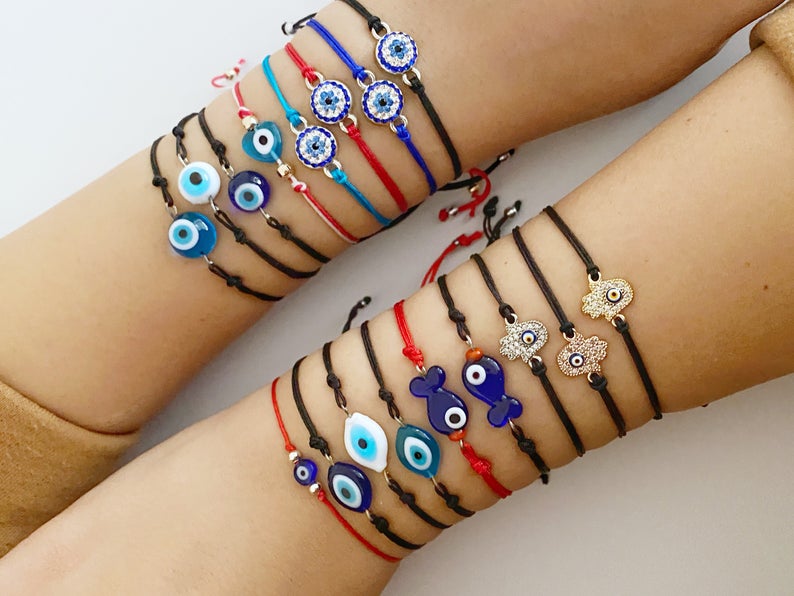 Evil Eye Thread Bracelet featuring a blue evil eye bead and adjustable string, adorned with a Hamsa charm.