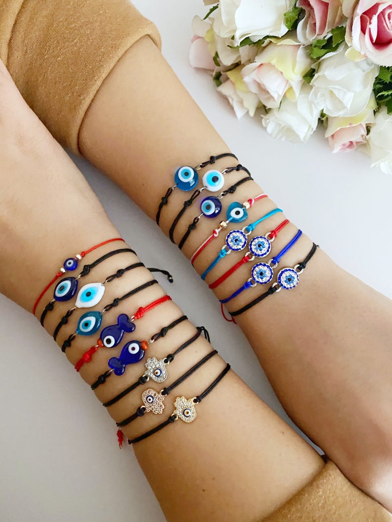 Evil Eye Thread Bracelet featuring a blue evil eye bead and adjustable string, adorned with a Hamsa charm.