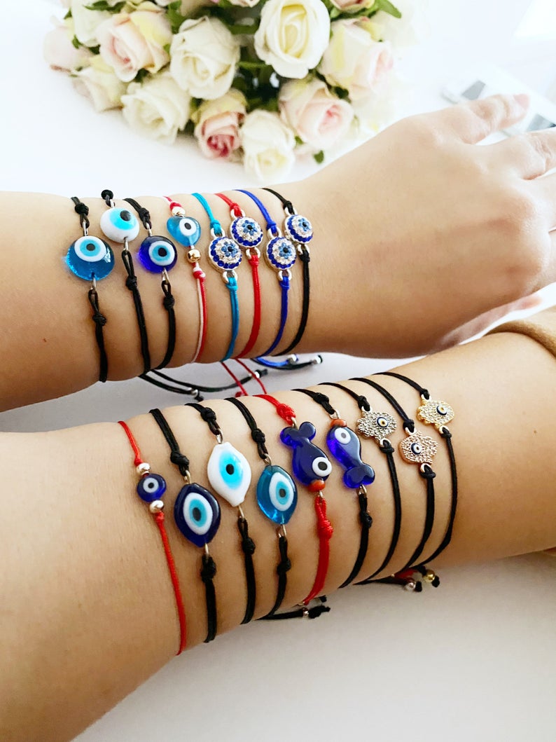 Evil Eye Thread Bracelet featuring a blue evil eye bead and adjustable string, adorned with a Hamsa charm.