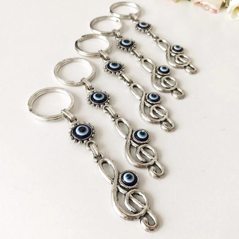 Evil Eye Treble Clef Keychain featuring a handmade blue glass charm and silver plated treble clef design.