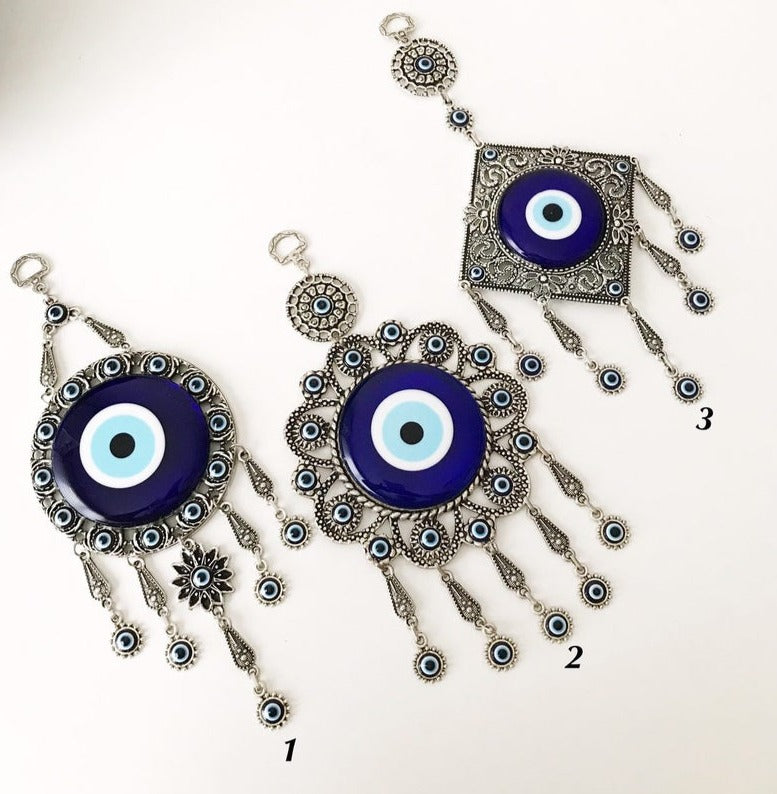 Evil eye wall decoration featuring blue glass beads and intricate metal designs, showcasing three unique styles.