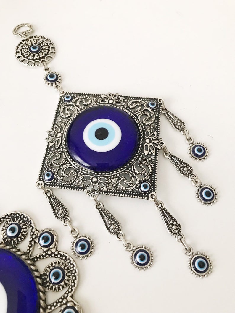 Evil eye wall decoration featuring blue glass beads and intricate metal designs, showcasing three unique styles.