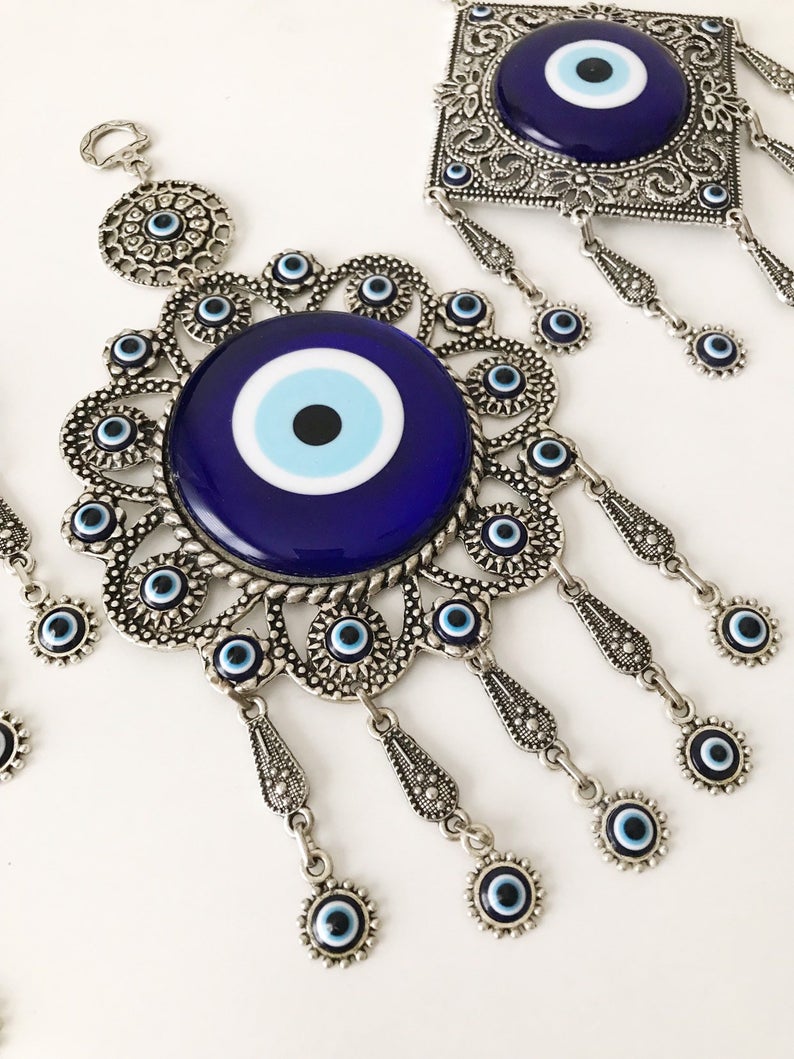 Evil eye wall decoration featuring blue glass beads and intricate metal designs, showcasing three unique styles.