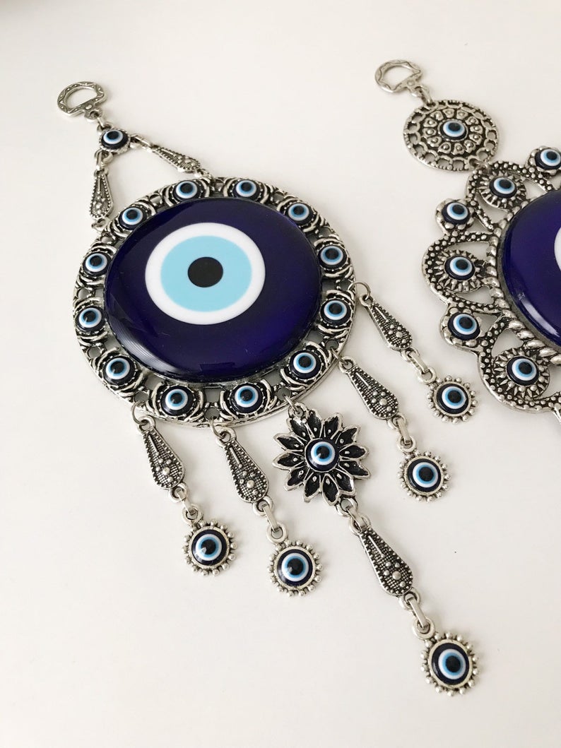 Evil eye wall decoration featuring blue glass beads and intricate metal designs, showcasing three unique styles.