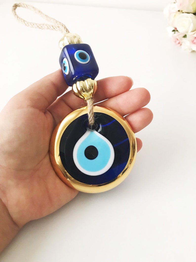 Handmade evil eye wall hanging with gold macrame and blue evil eye bead, perfect for home decoration and Christmas tree ornament.