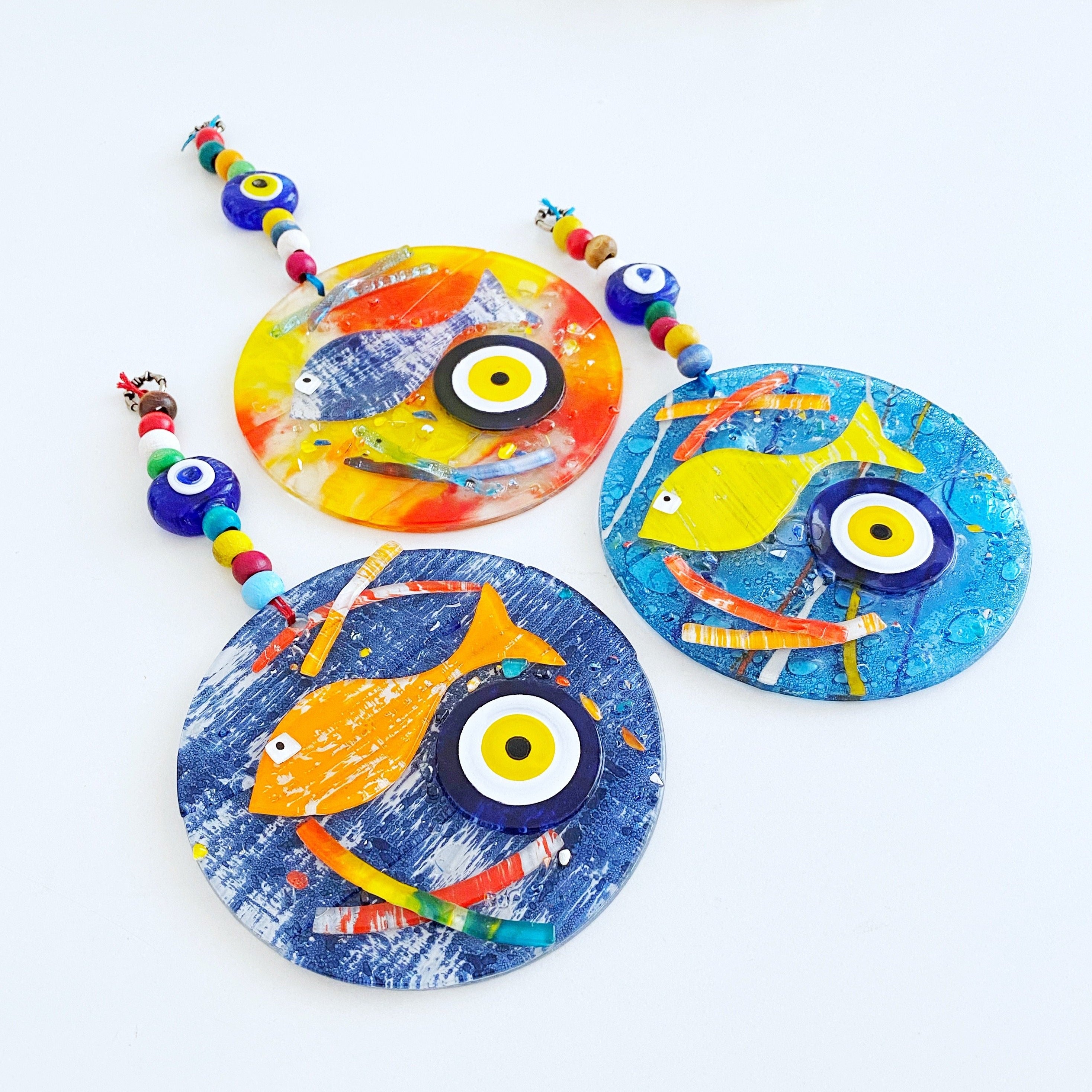 Handmade fused glass Evil Eye wall hanging featuring a fish design, vibrant colors, and unique craftsmanship, measuring 12cm x 12cm.