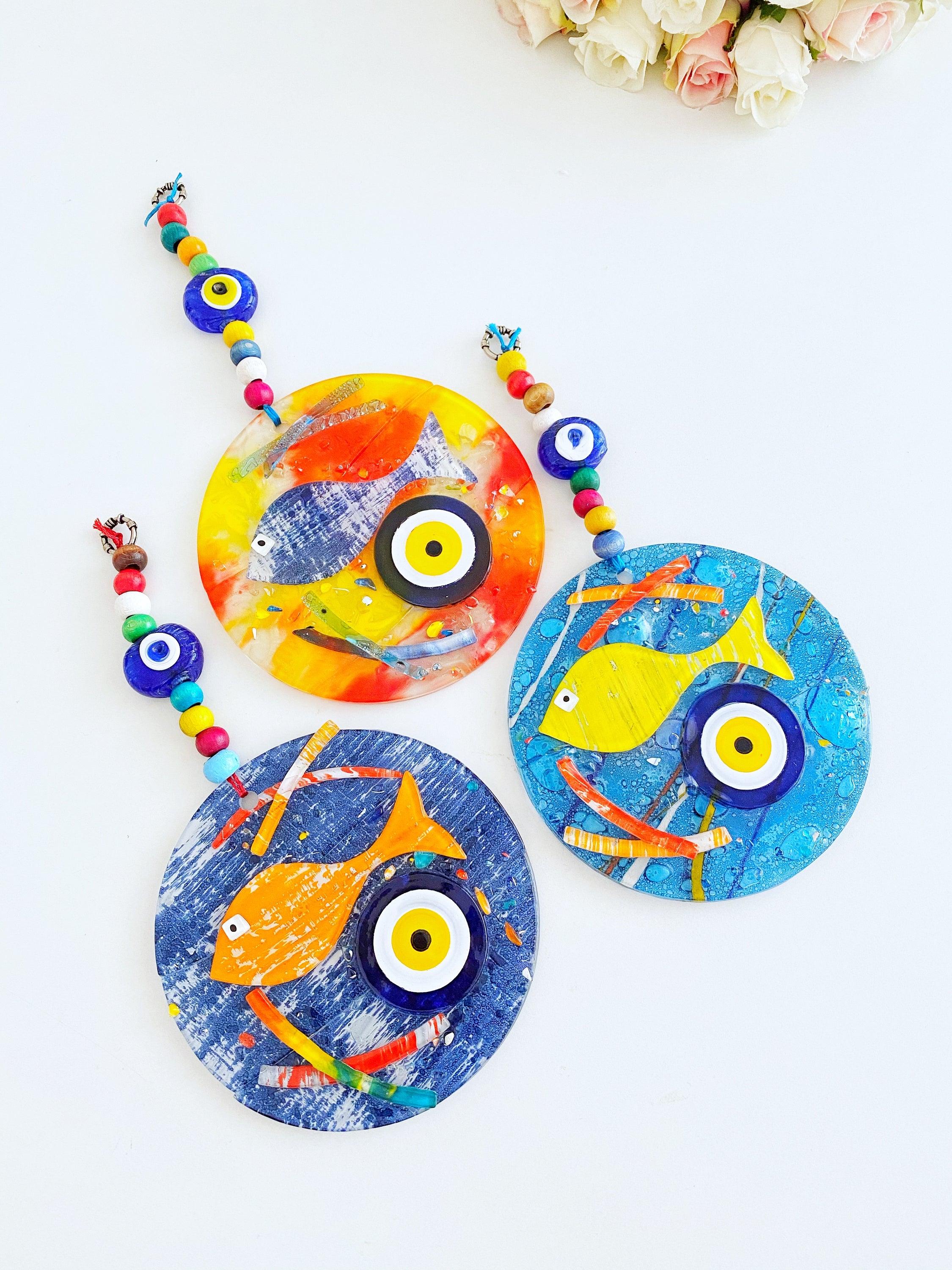 Handmade fused glass Evil Eye wall hanging featuring a fish design, vibrant colors, and unique craftsmanship, measuring 12cm x 12cm.